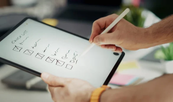 Person uses a stylus to check off items on a digital to-do list on a tablet screen.